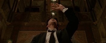 Movie still from “Constantine” (2005), directed by Francis Lawrence – A man wearing a suit and tie drinking a glass of water; Medium shot, Overhead angle