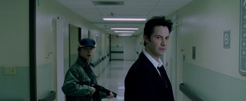 Movie still from “Constantine” (2005), directed by Francis Lawrence – A man and a woman standing in a hallway holding guns; Medium shot, Low angle
