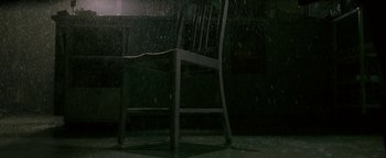 Movie still from “Constantine” (2005), directed by Francis Lawrence – A wooden chair sitting in the middle of a room; Wide shot, High angle