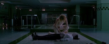 Movie still from “Constantine” (2005), directed by Francis Lawrence – A woman kneeling down next to a man laying on the ground; Wide shot, High angle