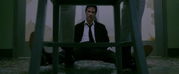 Movie still from “Constantine” (2005), directed by Francis Lawrence – A man in a suit and tie sitting on the ground; Medium shot, Low angle