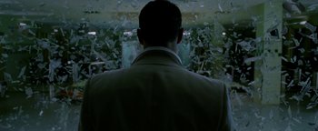 Movie still from “Constantine” (2005), directed by Francis Lawrence – A man standing in front of shattered glass in a room; Close Up shot, Over the shoulder angle