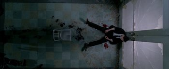 Movie still from “Constantine” (2005), directed by Francis Lawrence – A man in a suit and tie next to a chair and blood on the floor; Wide shot, Overhead angle