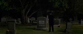 Movie still from “Constantine” (2005), directed by Francis Lawrence – A man standing in front of a grave in a cemetery; Wide shot, High angle