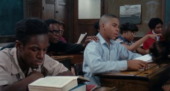 Movie still from “Cooley High” (1975), directed by Michael Schultz – A group of people sitting at a table with a book; Medium shot, Over the shoulder angle