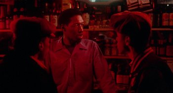 Movie still from “Cooley High” (1975), directed by Michael Schultz – A group of people standing in a room with bottles; Medium shot, Over the shoulder angle