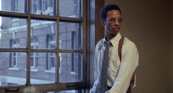 Movie still from “Cooley High” (1975), directed by Michael Schultz – A man standing in front of a window wearing glasses; Close Up shot, Low angle