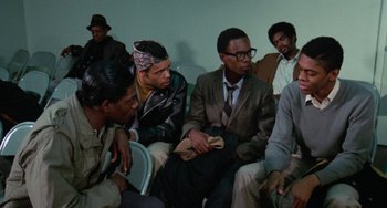 Movie still from “Cooley High” (1975), directed by Michael Schultz – A group of men sitting next to each other in a room; Medium shot, Over the shoulder angle