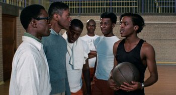 Movie still from “Cooley High” (1975), directed by Michael Schultz – A group of young men standing next to each other holding a basketball; Medium shot, Over the shoulder angle