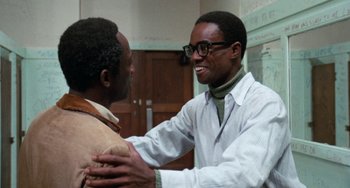 Movie still from “Cooley High” (1975), directed by Michael Schultz – A man in a white lab coat is hugging another man in a brown jacket; Medium shot, Over the shoulder angle