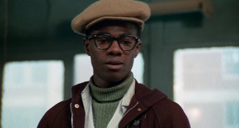 Movie still from “Cooley High” (1975), directed by Michael Schultz – A man wearing glasses and a hat is looking at the camera; Close Up shot, Low angle
