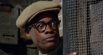 Movie still from “Cooley High” (1975), directed by Michael Schultz – A man wearing glasses and a hat leaning against a pole; Close Up shot, Low angle