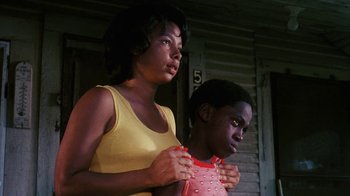 Movie still from “Coonskin” (1974), directed by Ralph Bakshi – A woman and a boy standing next to each other; Medium shot, Low angle