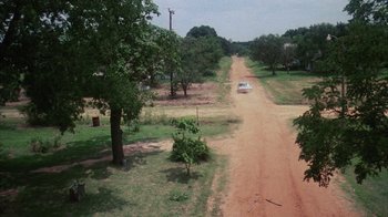 Movie still from “Coonskin” (1974), directed by Ralph Bakshi – An aerial view of a dirt road with a car on it; Extreme Wide shot, High angle