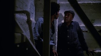 Movie still from “Coonskin” (1974), directed by Ralph Bakshi – Two men are standing in a room talking to each other; Medium shot, High angle