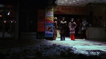 Movie still from “Coonskin” (1974), directed by Ralph Bakshi – A group of people standing on the sidewalk in front of a store; Extreme Wide shot, Low angle