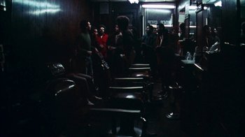 Movie still from “Coonskin” (1974), directed by Ralph Bakshi – A group of people standing in a room with chairs; Wide shot, High angle