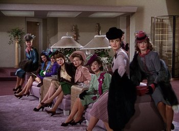Movie still from “Cover Girl” (1944), directed by Charles Vidor – A group of women sitting on top of couches in a room; Wide shot, Low angle