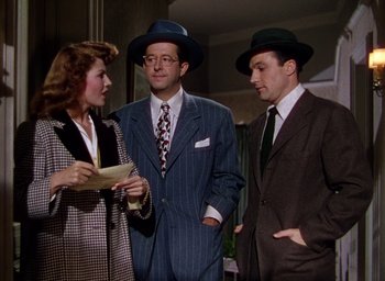 Movie still from “Cover Girl” (1944), directed by Charles Vidor – A group of people standing next to each other wearing hats; Medium shot, Low angle