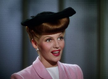 Movie still from “Cover Girl” (1944), directed by Charles Vidor – A woman in a pink jacket and a black hat; Close Up shot, Low angle