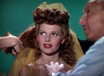 Movie still from “Cover Girl” (1944), directed by Charles Vidor – A woman with long red hair is getting her hair done; Close Up shot, Over the shoulder angle