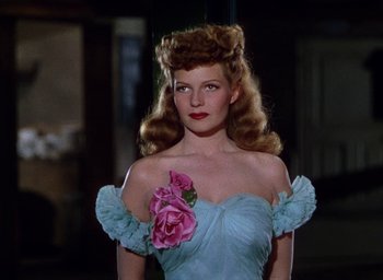 Movie still from “Cover Girl” (1944), directed by Charles Vidor – A woman in a blue dress holding a pink flower; Close Up shot, Low angle