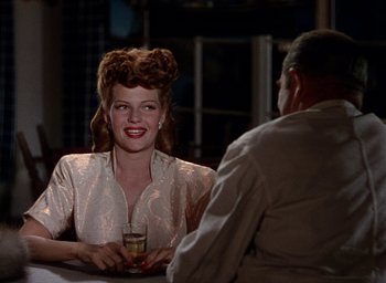 Movie still from “Cover Girl” (1944), directed by Charles Vidor – A woman sitting in front of a man at a table; Medium shot, Over the shoulder angle