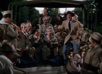 Movie still from “Cover Girl” (1944), directed by Charles Vidor – A group of people sitting in a room with instruments; Wide shot, High angle