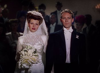 Movie still from “Cover Girl” (1944), directed by Charles Vidor – A man and a woman standing next to each other in formal wear; Medium shot, Low angle