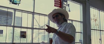 Movie still from “Crazy Heart” (2009), directed by Scott Cooper – A man wearing a white cowboy hat pointing to the side; Medium shot, Over the shoulder angle