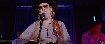 Movie still from “Crazy Heart” (2009), directed by Scott Cooper – A man in a cowboy hat is holding a guitar; Close Up shot, Low angle