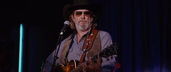 Movie still from “Crazy Heart” (2009), directed by Scott Cooper – A man with a beard wearing a hat and holding a guitar; Medium shot, Low angle