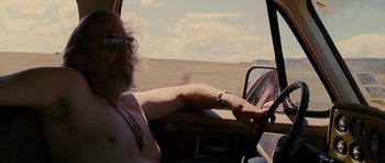 Movie still from “Crazy Heart” (2009), directed by Scott Cooper – A man driving a car in the middle of the desert; Medium shot, Low angle