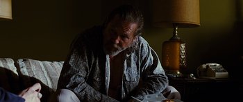 Movie still from “Crazy Heart” (2009), directed by Scott Cooper – A man with a beard is sitting at a table with food in front of him; Medium shot, Over the shoulder angle