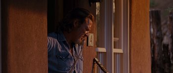 Movie still from “Crazy Heart” (2009), directed by Scott Cooper – A man with long hair and a goatee leaning against a wall with a guitar; Medium shot, Low angle