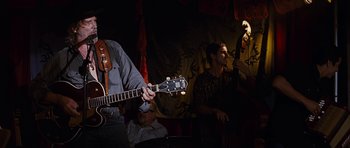 Movie still from “Crazy Heart” (2009), directed by Scott Cooper – A man playing a guitar while another man plays a double bass; Medium shot, Low angle