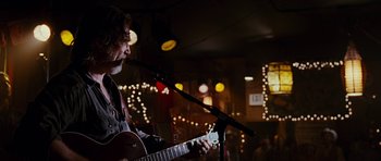 Movie still from “Crazy Heart” (2009), directed by Scott Cooper – A man with a beard is playing a guitar; Close Up shot, Low angle