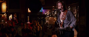 Movie still from “Crazy Heart” (2009), directed by Scott Cooper – A man with a beard is playing a guitar; Medium shot, Over the shoulder angle