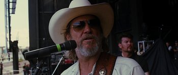 Movie still from “Crazy Heart” (2009), directed by Scott Cooper – A man with a white cowboy hat and a microphone; Close Up shot, Over the shoulder angle