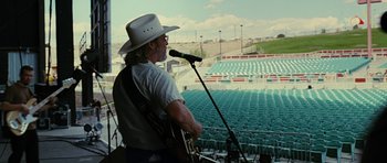 Movie still from “Crazy Heart” (2009), directed by Scott Cooper – A man in a white cowboy hat holding a microphone; Wide shot, Over the shoulder angle