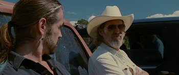 Movie still from “Crazy Heart” (2009), directed by Scott Cooper – A man in a white hat and sunglasses next to a car; Medium shot, Over the shoulder angle
