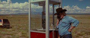 Movie still from “Crazy Heart” (2009), directed by Scott Cooper – An older man talking on a phone in front of a phone booth; Wide shot, Low angle
