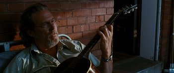 Movie still from “Crazy Heart” (2009), directed by Scott Cooper – A man holding a guitar in front of a brick wall; Close Up shot, Low angle