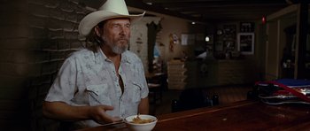 Movie still from “Crazy Heart” (2009), directed by Scott Cooper – A man sitting at a table with a bowl of food; Medium shot, Over the shoulder angle