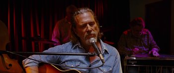 Movie still from “Crazy Heart” (2009), directed by Scott Cooper – A man with long hair and a goatee is playing a guitar; Close Up shot, Low angle