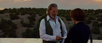 Movie still from “Crazy Heart” (2009), directed by Scott Cooper – A man with long white hair and a beard is looking at a cell phone; Medium shot, Over the shoulder angle