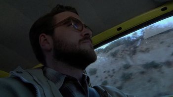 Movie still from “Creep” (2014), directed by Patrick Brice – A man with a goatee wearing glasses driving a car; Close Up shot, Low angle
