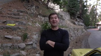 Movie still from “Creep” (2014), directed by Patrick Brice – A man standing in front of a rock wall; Medium shot, Low angle