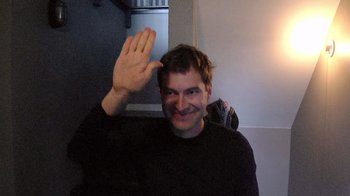 Movie still from “Creep” (2014), directed by Patrick Brice – A man holding his hand up to the side of his face; Medium shot, High angle