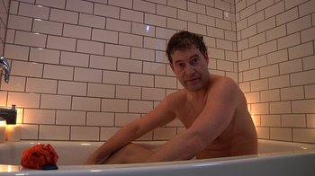 Movie still from “Creep” (2014), directed by Patrick Brice – A man sitting in a bath tub in front of a tiled wall; Medium shot, Low angle